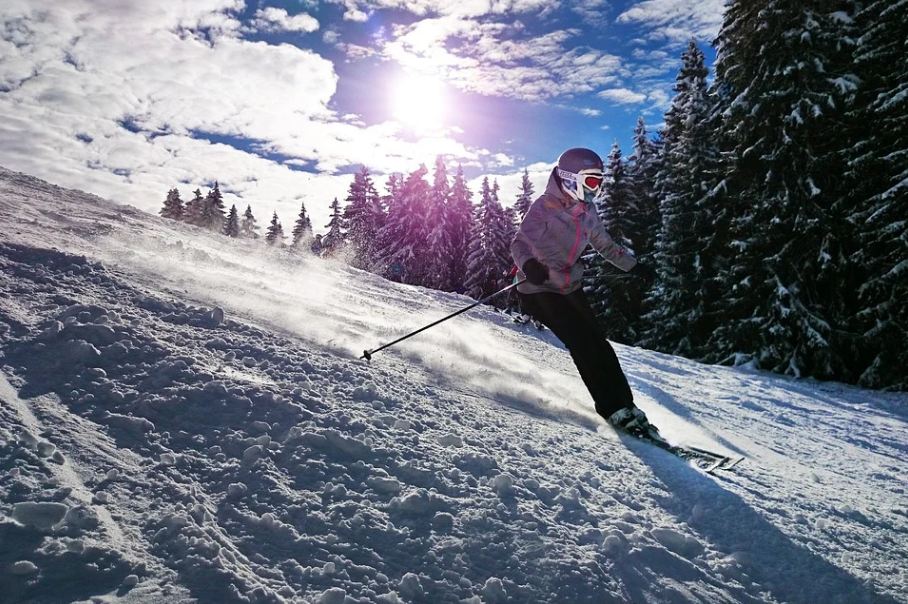 a skier skiing down a slope terrain on a sunny day