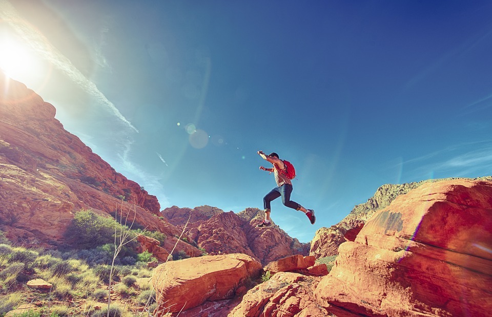 a hiker jumping from one rock to another