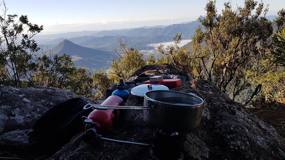 overview of mountains, green trees, cooking tools and equipment placed on a big rock