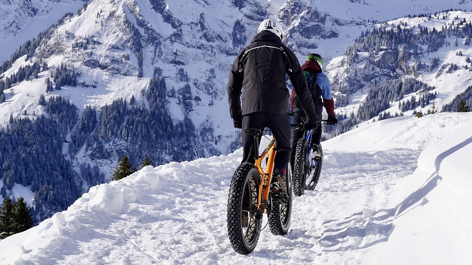 two bikers riding their bike on a snowy mountain track