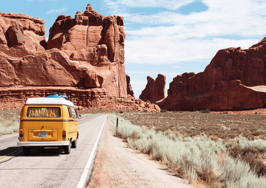 A yellow van captured on the road surrounded by mountains 