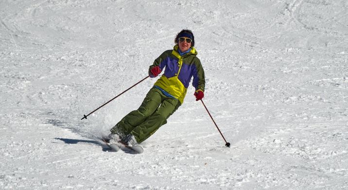a man in a ski outfit and holding ski equipment skiing